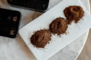 Comparación de tres tamaños diferentes de molienda de café, desde gruesa hasta fina, en un plato blanco.