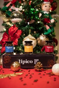 Caja de regalo de café Típico con tres frascos de café, rodeada de decoración navideña.