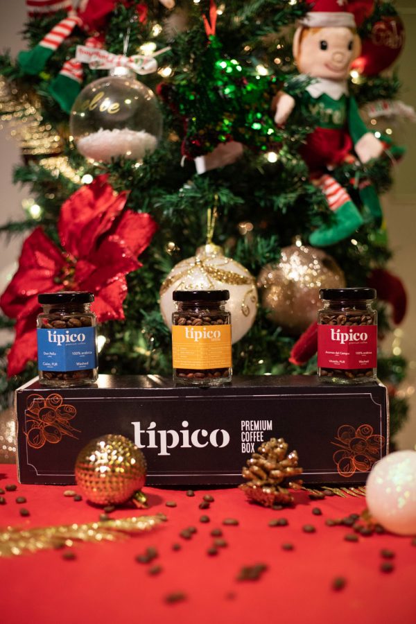 Caja de regalo de café Típico con tres frascos de café, rodeada de decoración navideña.